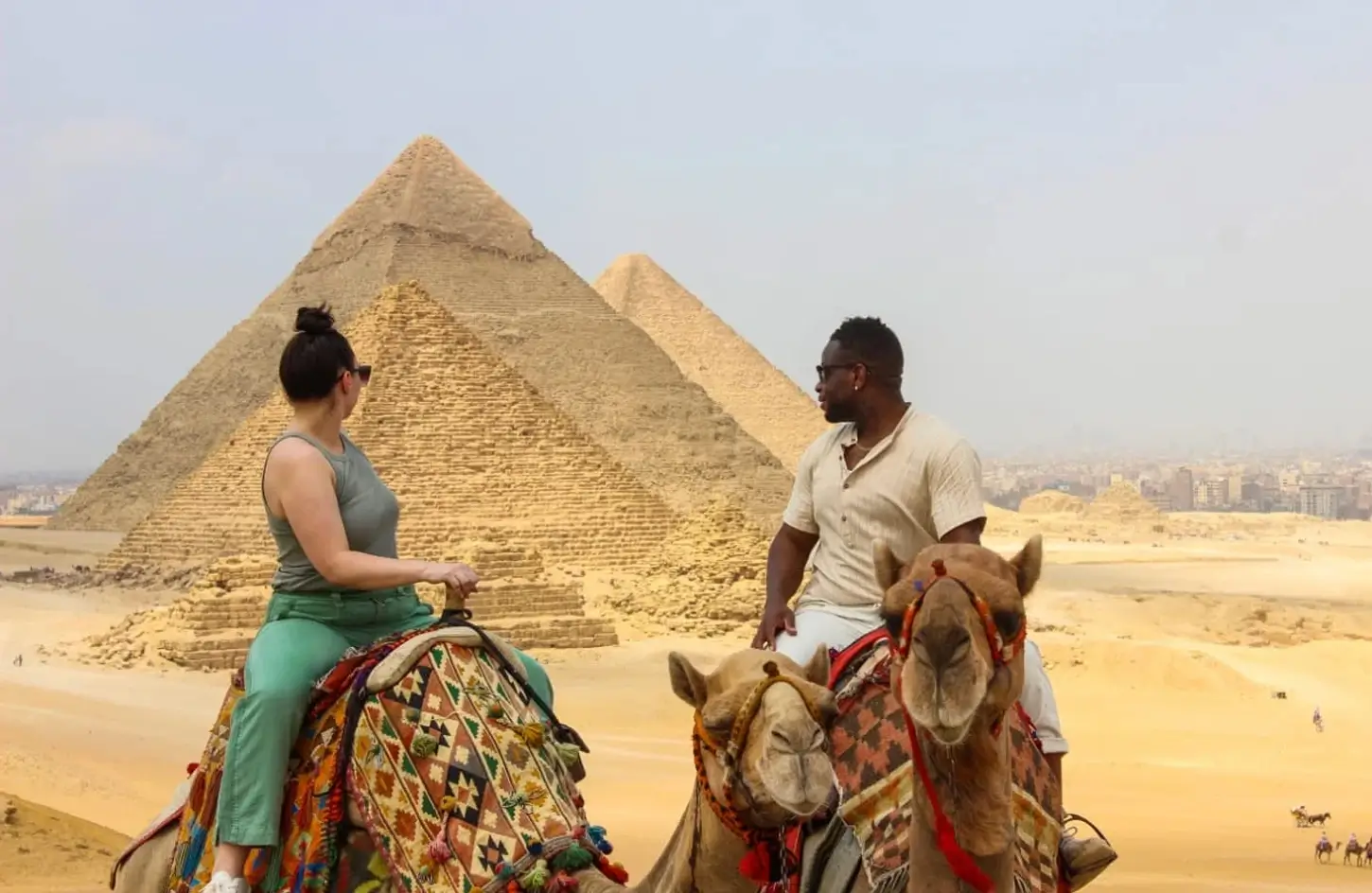 A couple riding camels in front of the Great Pyramid of Giza
